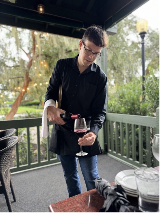 waiter pouring a bottle of wine into wine glass